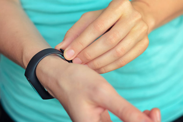 young woman put on fitness tracker on her hand - Fotó, kép