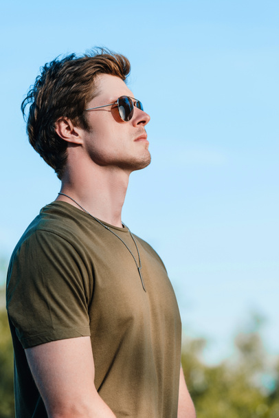side view of confident soldier in sunglasses against blue sky - Photo, Image