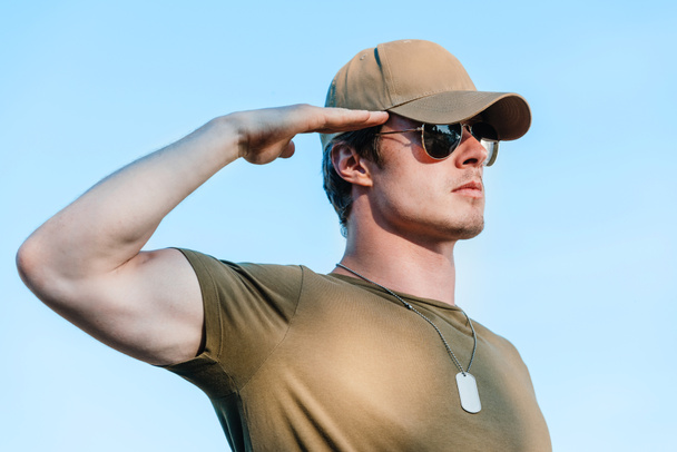 vue latérale du jeune soldat en casquette et lunettes de soleil contre le ciel bleu
 - Photo, image