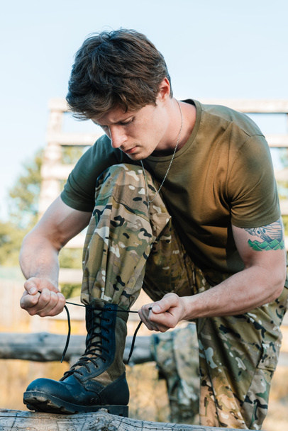 retrato de soldado em uniforme militar amarrando cadarços
 - Foto, Imagem