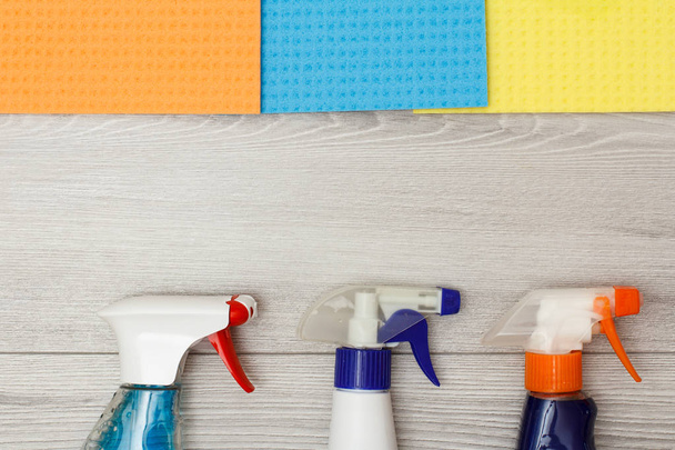 Butelki z detergentem i kolor z mikrofibry do czyszczenia na szarym tle drewnianych z kopii przestrzeni w centrum. Zestaw do czyszczenia narzędzi i sprzętu - Zdjęcie, obraz