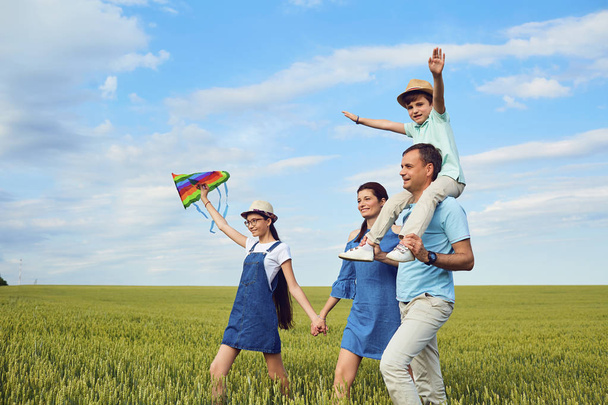 Family with a kite walking on the field in nature. - Zdjęcie, obraz