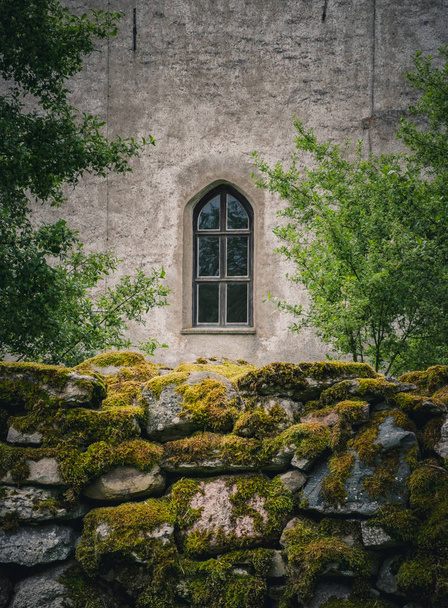 Old window on the church and stone wall with moss - Φωτογραφία, εικόνα