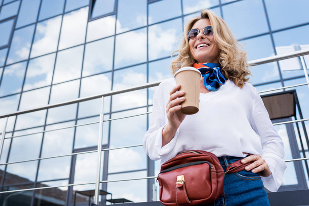 low angle view of attractive woman holding coffee in paper cup on street  - Foto, immagini
