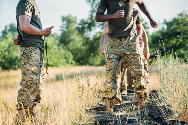 Μερική άποψη της τακτικής εκπαιδευτή με χρονόμετρο και διαφυλετικός στρατιωτών εν ενεργεία με λάστιχα στο έδαφος στην περιοχή - Φωτογραφία, εικόνα