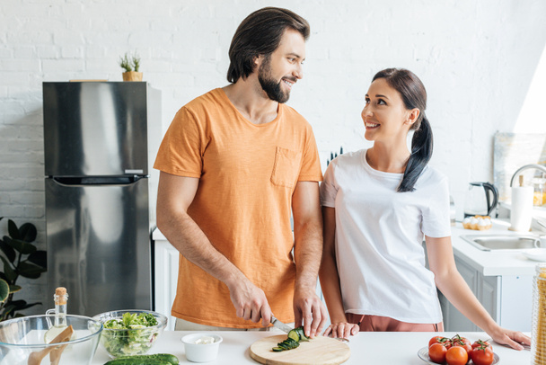 happy adult couple preparing salad together at kitchen - Photo, image