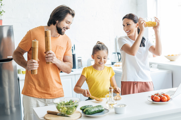 όμορφη νεαρή οικογένεια παίζει μουσική με μαγειρικά σκεύη και τη διασκέδαση στην κουζίνα - Φωτογραφία, εικόνα