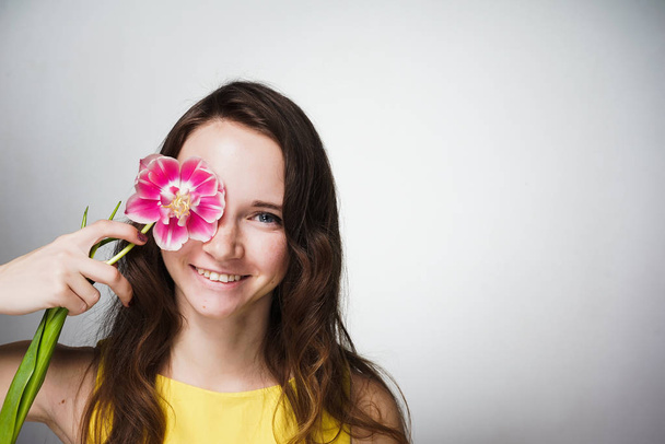 cute beautiful smiling girl holding a fragrant pink flower near the face - 写真・画像