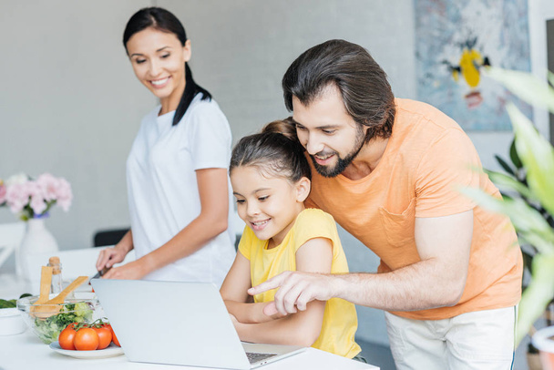 beautiful young family using laptop together at kitchen - Φωτογραφία, εικόνα