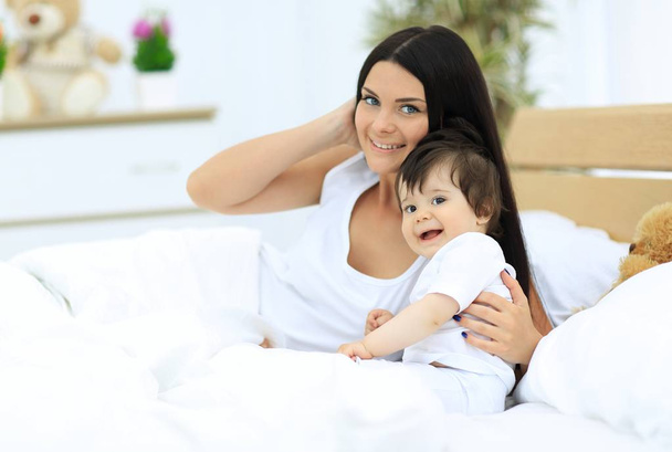 Portrait of a beautiful mother with her baby in the bedroom - Photo, Image