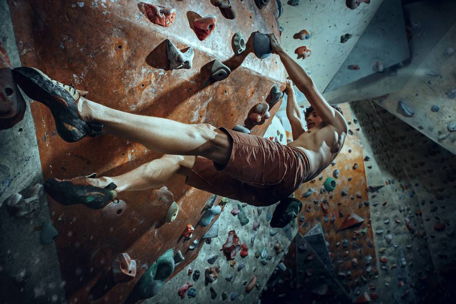 Free climber young man climbing artificial boulder indoors - Foto, imagen