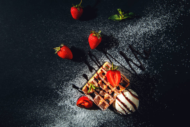 Belgian waffles with ice cream and strawberries on a black background. - Foto, Bild