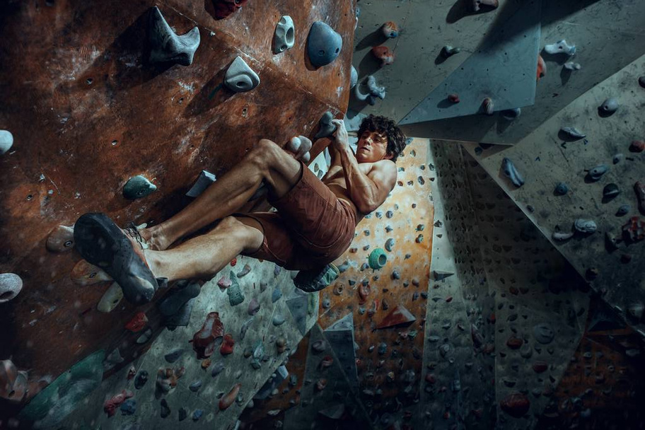 Free climber young man climbing artificial boulder indoors - Photo, image