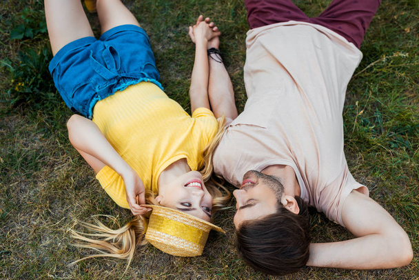 overhead view of couple in love resting on green grass in park - Φωτογραφία, εικόνα