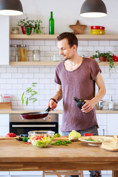 Portrait of man with frying pan in hands in kitchen - Foto, Bild