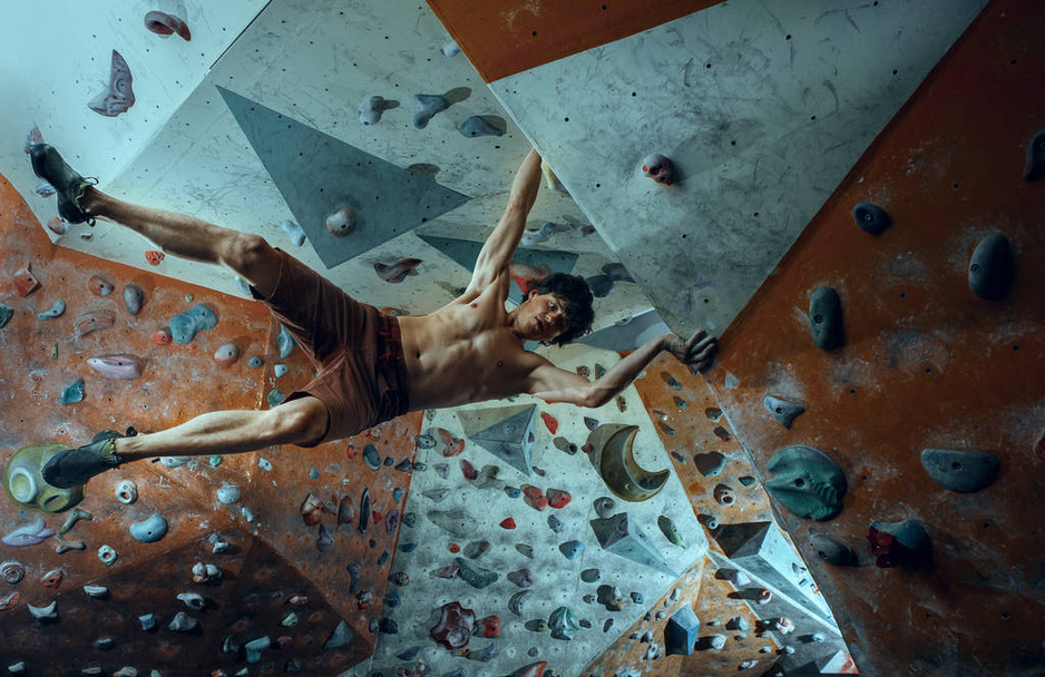 Free climber young man climbing artificial boulder indoors - Photo, image