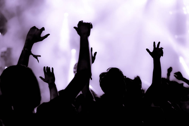 Фіолетовий фільтрований натовп на музичному концерті з піднятими руками вгору
 - Фото, зображення
