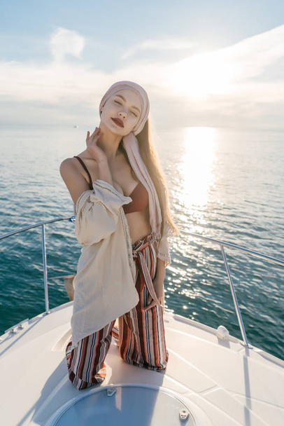 confident luxury girl in stylish clothes resting on a yacht, posing in the sun - 写真・画像