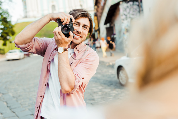 partial view of smiling man taking picture of girlfriend on photo camera on street - Photo, image