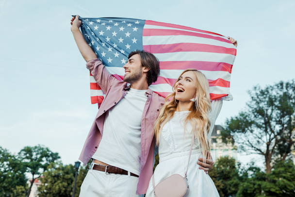 幸せな若いカップル、アメリカ独立記念日の概念の手でアメリカの国旗を保持 - 写真・画像