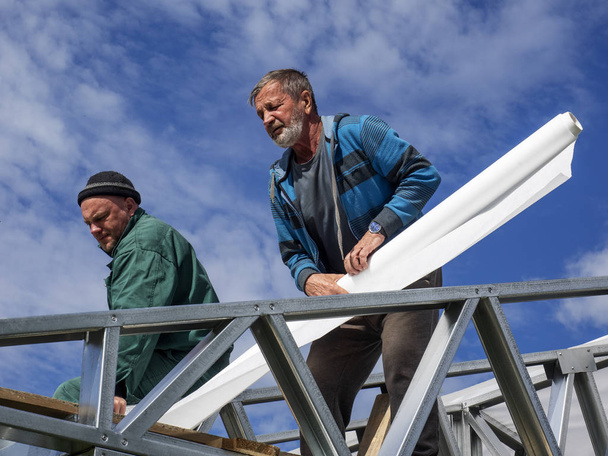 Caucasian men performs roofing work. Installation of moisture barrier - Фото, зображення