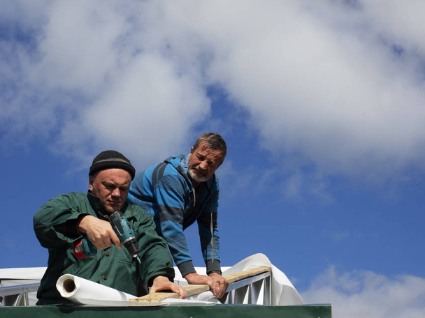Caucasian men performs roofing work. Installation of moisture barrier - Foto, afbeelding