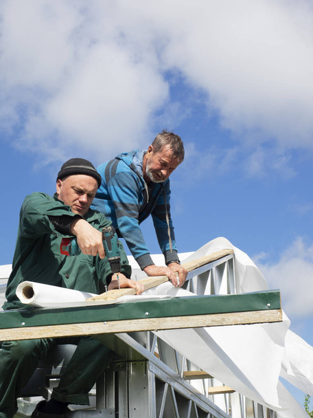 Caucasian men performs roofing work. Installation of moisture barrier - Foto, imagen