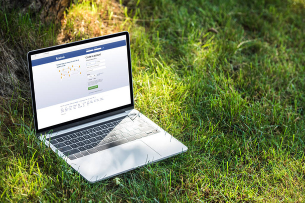 vista de cerca de la computadora portátil con facebook sitio web en la hierba al aire libre
  - Foto, Imagen