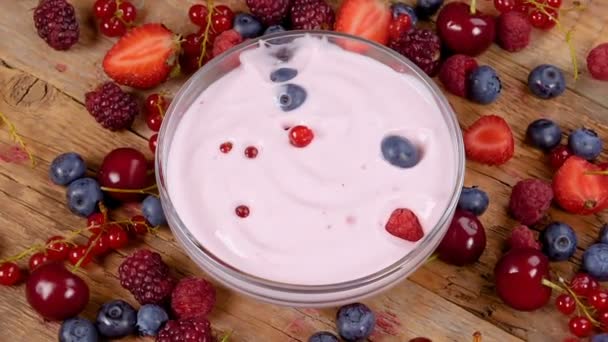 Forest fruits falling in yogurt. Healthy breakfast concept with yogurt and fruits on rotating table.  - Footage, Video