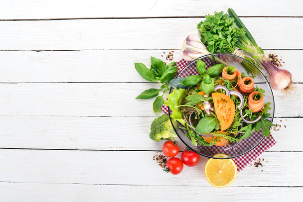 Fresh Vegetable Salad. Arugula, tomatoes, carrots, onions. On a wooden background. Top view. Copy space. - Foto, imagen