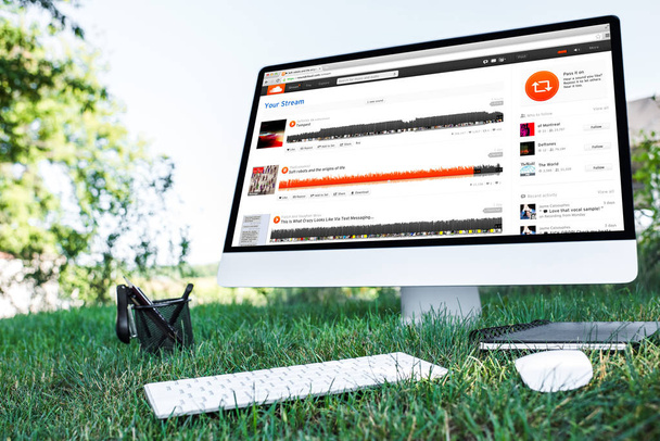 selective focus of textbook and computer with soundcloud website on grass outdoors  - Φωτογραφία, εικόνα