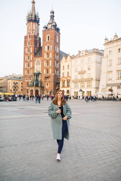 Happy traveler girl posing on Main Square of Krakow, Poland. View to Basilica of Saint Mary. - Φωτογραφία, εικόνα