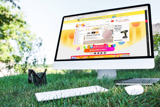 selective focus of textbook and computer with aliexpress website on grass outdoors  - Fotografie, Obrázek