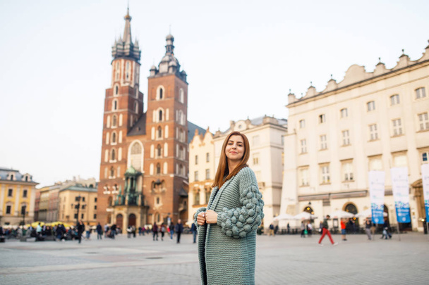 Happy traveler girl posing on Main Square of Krakow, Poland. View to Basilica of Saint Mary. - Foto, Imagem