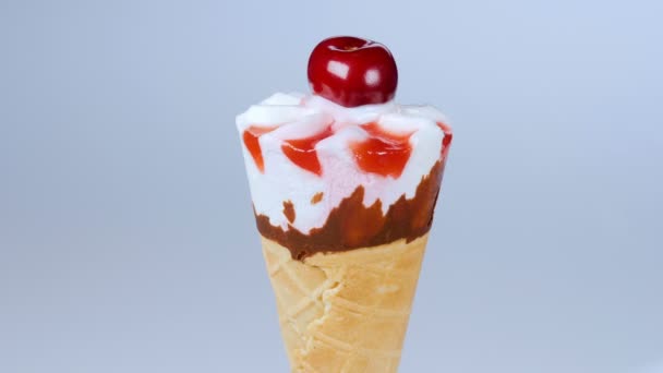 Vanille-ijs in kegel met cherry draaien op blauwe achtergrond. 4k - Video
