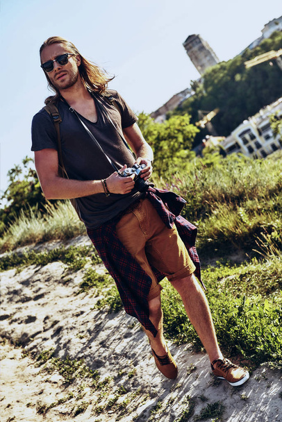 full length of young man with camera walking on hill outdoors - Valokuva, kuva