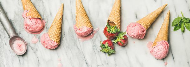 Homemade yogurt ice cream with strawberries in waffle cones over grey marble background - Photo, image