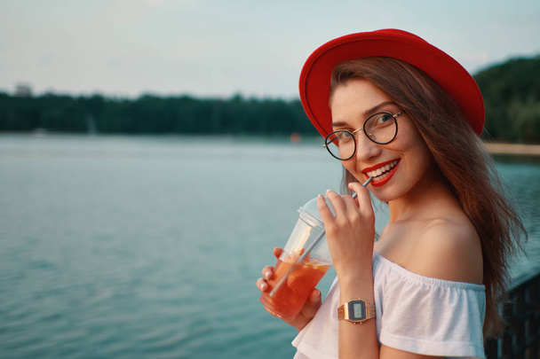 Una mujer joven y elegante tomando una bebida refrescante mientras busca
 - Foto, imagen