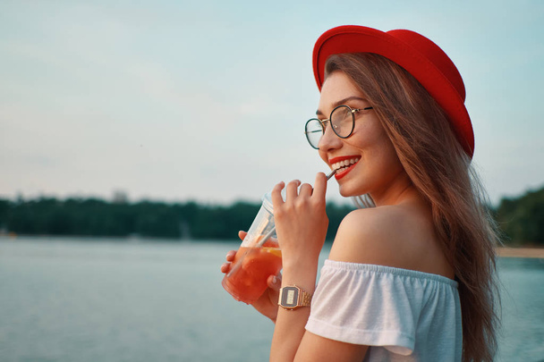 A Young stylish woman having a refreshing drink while walking - Photo, image