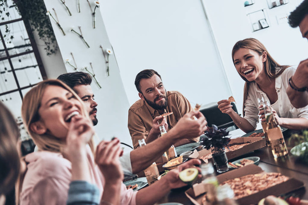 laughing young people in casual wear eating pizza at table  - Фото, зображення