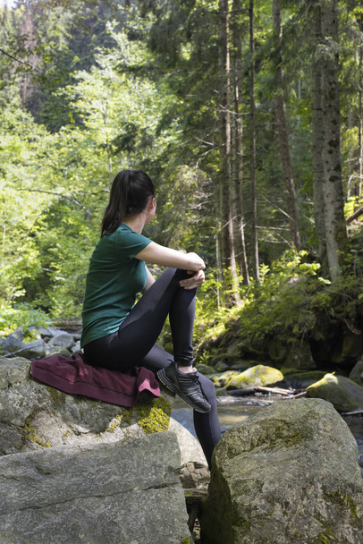 Στοχαστικός κορίτσι κάθεται σε έναν βράχο στο δάσος. Μέρα του καλοκαιριού - Φωτογραφία, εικόνα