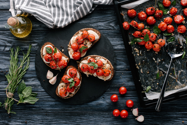 Delicious sandwiches with mozzarella and baked tomatoes on dark slate board - Fotoğraf, Görsel