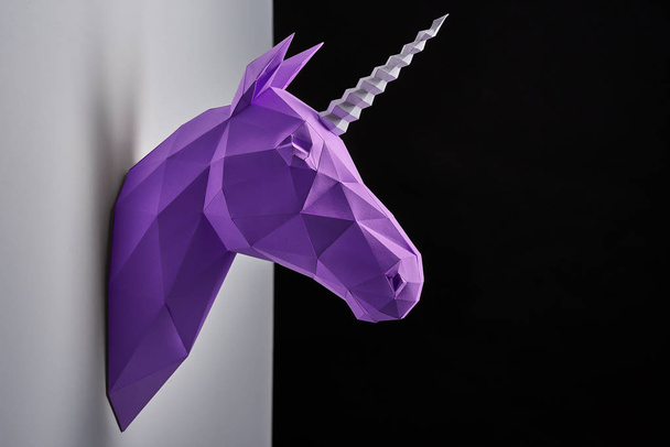 Horizontal shoot of violet unicorns head hanging on grey shadowed wall. - Foto, Imagem