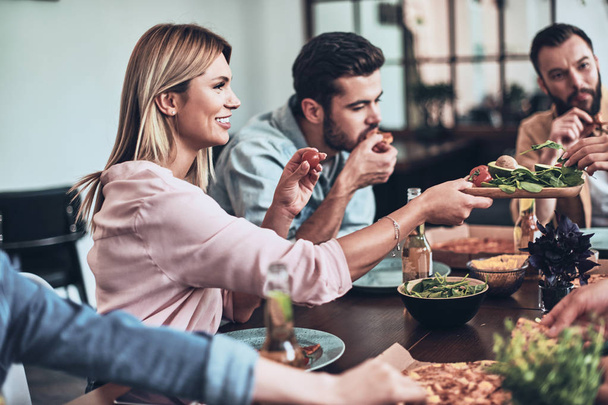 hungry people in casual wear eating pizza at table - Фото, изображение