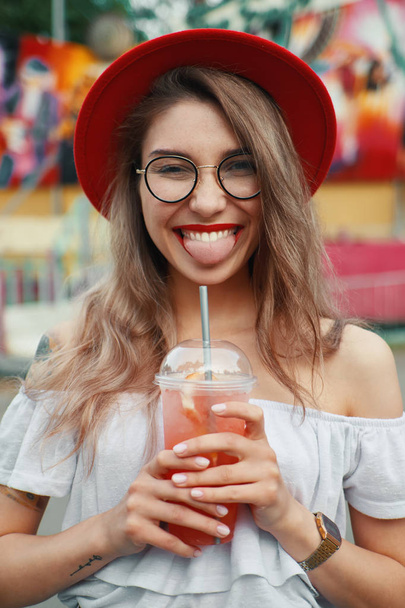 Веселая молодая женщина, держа напиток, улыбаясь
 - Фото, изображение