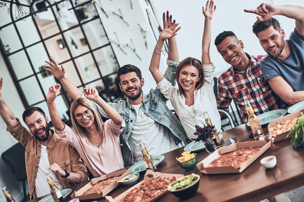 happy young people in casual wear gesturing with hands raised and smiling while having dinner party - Photo, image