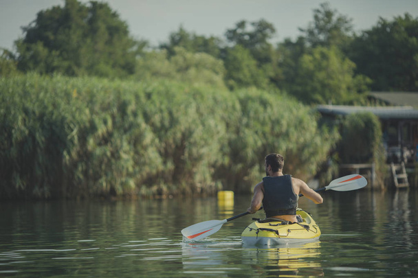 Back view of a man kayaker paddling on the river. - Fotografie, Obrázek