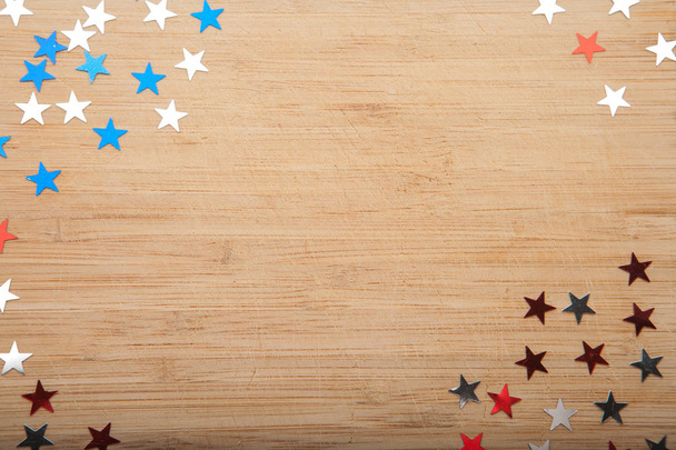 Konfettisterne auf hölzernem Hintergrund. 4. Juli, Unabhängigkeitstag, Karte, Einladung in den US-Flaggenfarben. Blick von oben, leerer Raum. - Foto, Bild