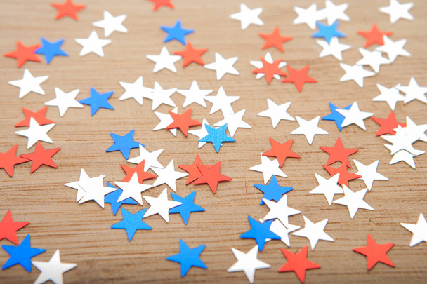 Звезды Конфетти на деревянном фоне. 4 июля, День независимости, карточка, приглашение в цветах флага США. Вид сверху, пустое пространство
. - Фото, изображение