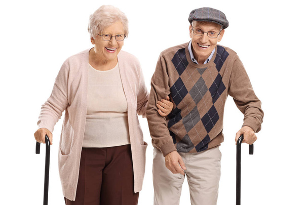 Elderly couple with canes looking at the camera and smiling isolated on white background - 写真・画像
